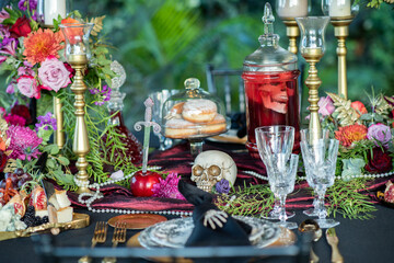 Table with skulls and tableware served for Halloween holiday