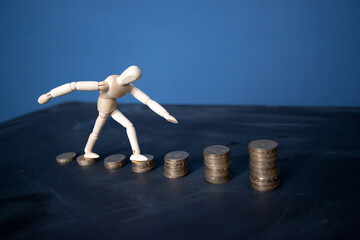 Stacks of golden coins like income graph and wooden man walking.