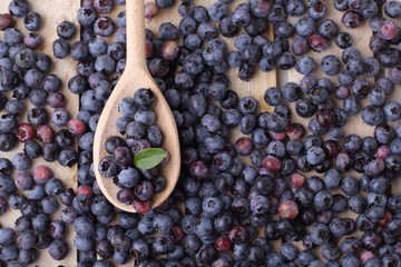 Blueberry in wooden spoon on wooden tray.  Ripe And Juicy Fresh Berries with green leaf. Copy space