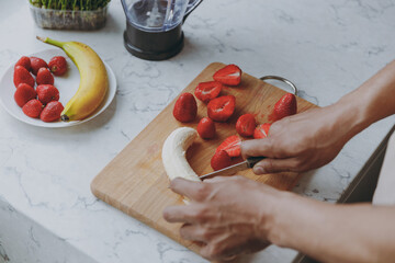 Cropped close up photo shot of young man male hands prepare sweet salad breakfast chop cut fruit...