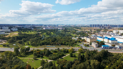 Fototapeta na wymiar City landscape. Nearby there is a park area. Blue sky with white clouds. Aerial photography.