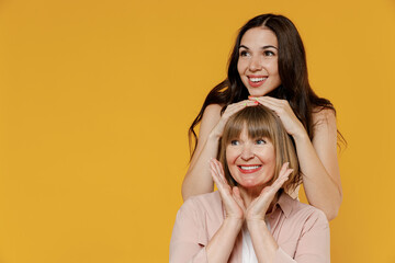Two young smiling happy cheerful daughter mother together couple women in casual beige clothes look aside hug posing isolated on plain yellow color background studio portrait Family lifestyle concept.