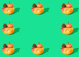 Creative autumn pattern made of pumpkins, pine cones and leaves on green background. Minimal seasonal concept with copy space. Halloween or Thanksgiving composition.