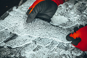 Pieces of broken toughened glass, hands in gloves