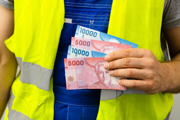 Worker counting his earnings, Chile money, Concept of wages and labor costs in industry