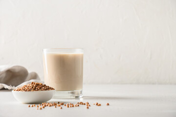 Lactose free healthy buckwheat milk served in drinking glass with grain ingredient on a white background. Horizontal orientation. Copy space.