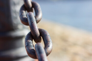 Heavy forged chain on the fence of the Neva embankment. The links of an old chain, illuminated by the sun, close-up.