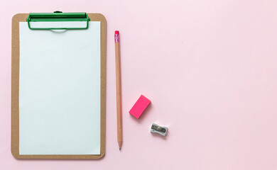 Fototapeta na wymiar School supplies, blank paper clipboard, pencil eraser and sharpener on pink background, top view