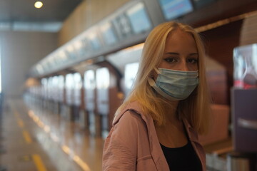 teenage girl with blonde hair standing near the information board to the airport