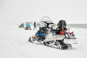 Winter entertainment. In the foreground is a snow-covered snowmobile without a driver, in the...