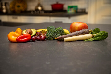 Fruit and vegetable arrangement in a kitchen including bananna, apple, grapes, broccoli, avacado,...