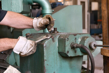The worker installs the fixture on the machine bed by tightening the nuts with a wrench.