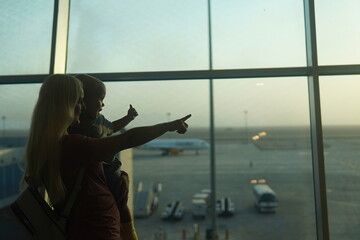 mother and son looking at the plane to the airport. Waiting flight.