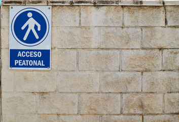 Spanish walking acces only sign on a blocks wall