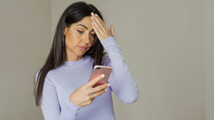 Naklejka premium Beautiful Sad ,Worried Unhappy Woman Sitting at Home and Looking at her Smartphone 