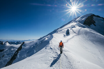 Voor de Mont Blanc (Monte Bianco) top 4808m laatste beklimming. Team roping up Man met klimbijl gekleed op grote hoogte bergbeklimmen kleding met rugzak wandelen door besneeuwde hellingen met blauwe lucht.