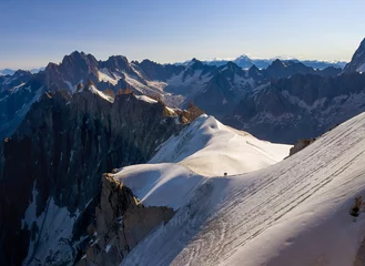 Wall murals Mont Blanc French Alps mountains peaks panorama view with silhouettes of climbers as roping team descending on the snowy slope under Aiguille du Midi 3842m. Beauty of Nature and extreme people activity concept.