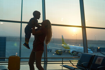 mother meet her son at the airport and pick him up in his arms.