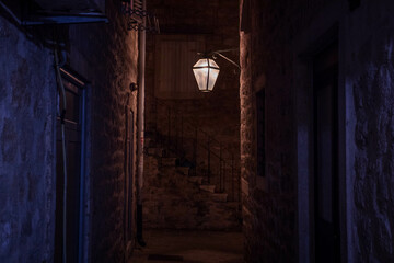 Fototapeta na wymiar Medieval narrow orange lit alley at night in old town with a lantern