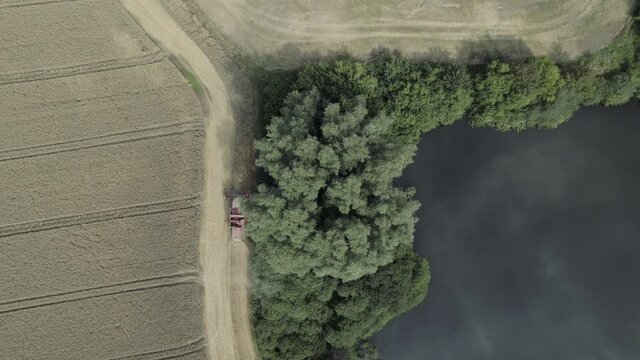 Aerial bird's eye view of Harvester harvests in the field close to a lake agriculture