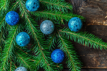 christmas festive background of spruce sprigs decorated with blue christmas toys on an old wooden surface