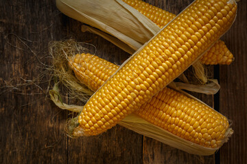 Fresh corn on the cob on a rustic wooden table, close up.