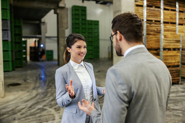 Warehouse and management. A man and a woman in a business suit stand in a warehouse and talk about...
