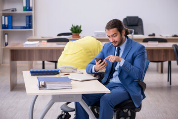 Young male employee looking after new born at workplace