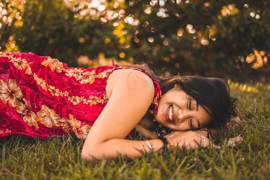 Girl in red  floral dress lying on green grass
