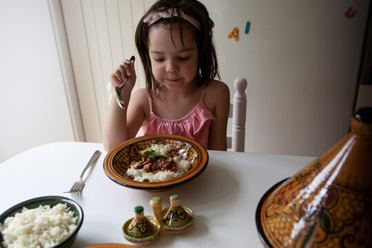 Girl in pink tank top eating rice and meat