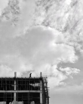 Grayscal photo of man standing on rooftop of construction site u