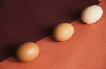 Three chicken eggs are laid on paper of natural colors. The texture of the paper and the egg is beige.Easter eggs.