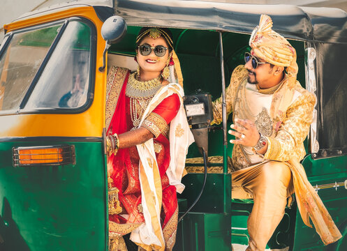 Indian bride and groom in traditional wedding outfit sitting in tuk-tuk