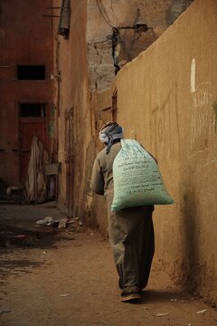 Man holding a sack oh his back walking in alley