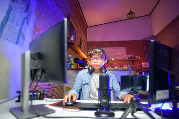 Man sitting beside microphone and two computer screens