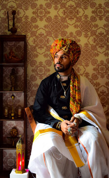 man wearing traditional dress sitting on chair beside display cabinet