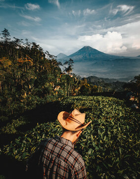Man wearing square patterned shirt and cowboy hat with nature view