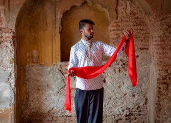 Man with red textile dancing in a a brown building