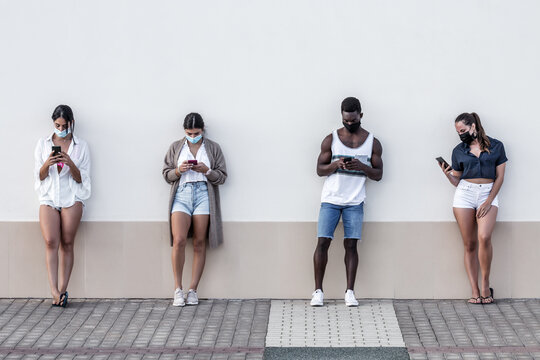 People leaning on wall looking at their cellphones