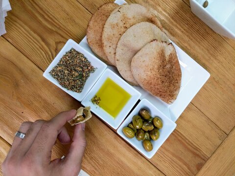 Person Eating Thyme, And Olives With Pita Bread