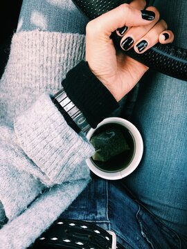 person holding black car steering wheel with coffee mug between legs