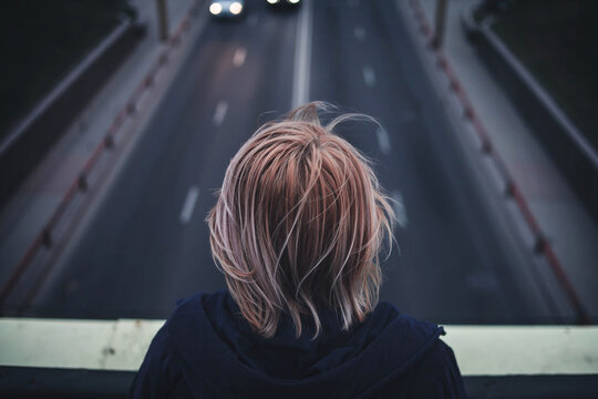 Person standing on bridge facing freeway