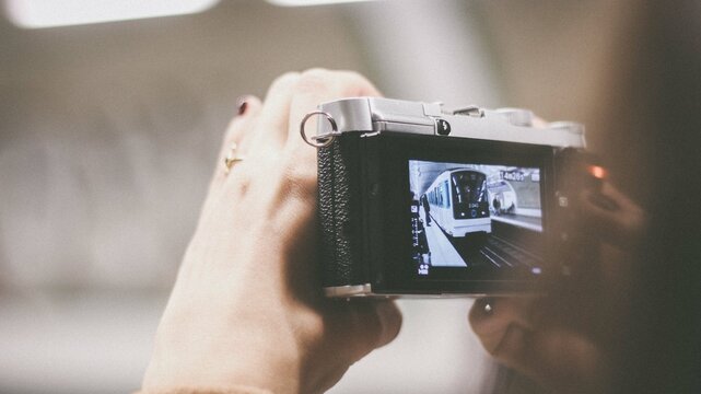 person taking photo of train with a digital camera