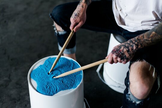Persone drumming on bucket with blue powder