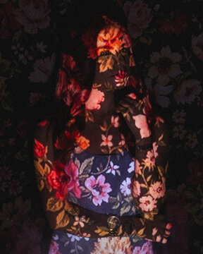 Portrait of a woman with screen projector projecting floral pattern on her