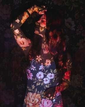 Portrait of a woman with screen projector projecting floral pattern on her