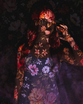Portrait of a woman with screen projector projecting floral pattern on her