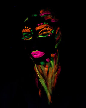 portrait of a woman with neon face paint in the dark