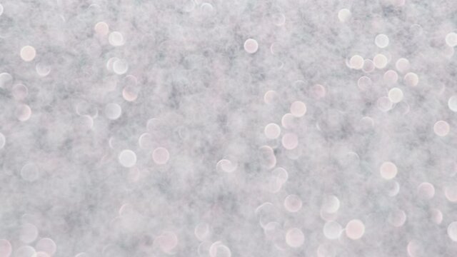 Shiny glitter silver blurred glow background. Shimmering light sparkling texture. Abstract motion festive background.