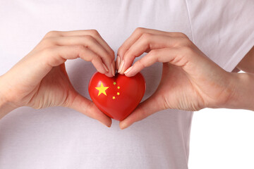 Woman with small heart in colors of Chinese flag, closeup